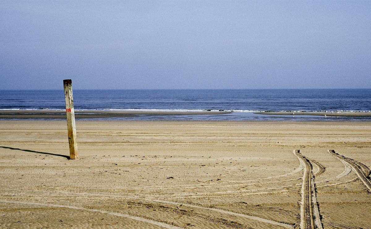 Sporen van auto's op het strand