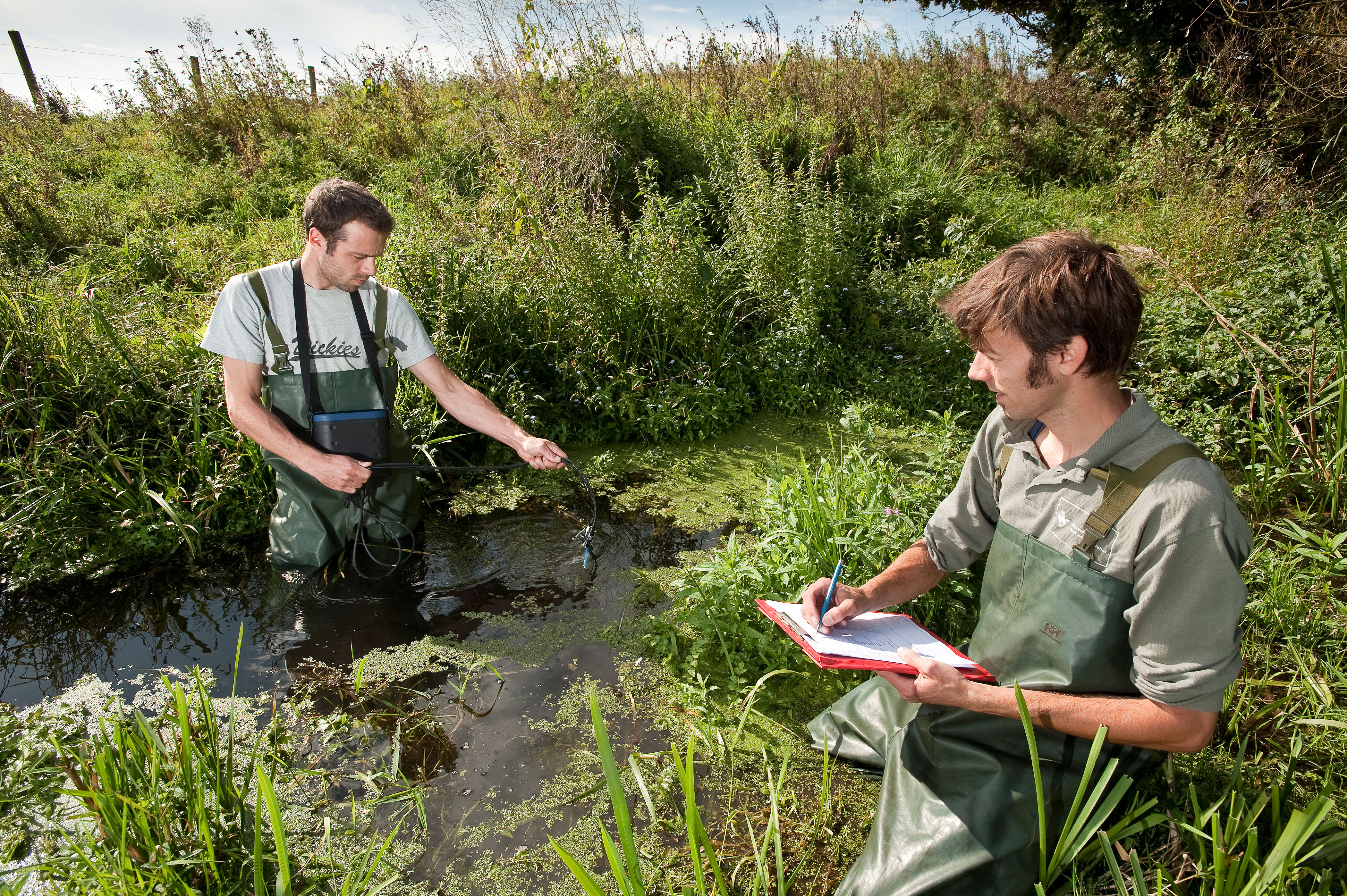 Twee waterschapsmedewerkers controleren de waterkwaliteit