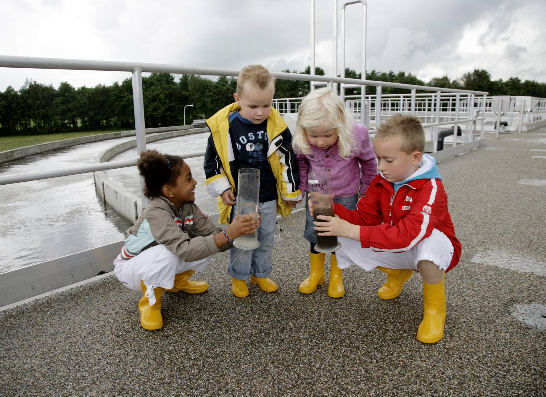 Kinderen met watermonsters op rioolwaterzuiveringsinstallatie