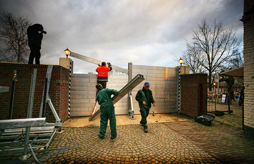 Medewerkers van een waterschap plaatsen coupures in verband met hoog water.