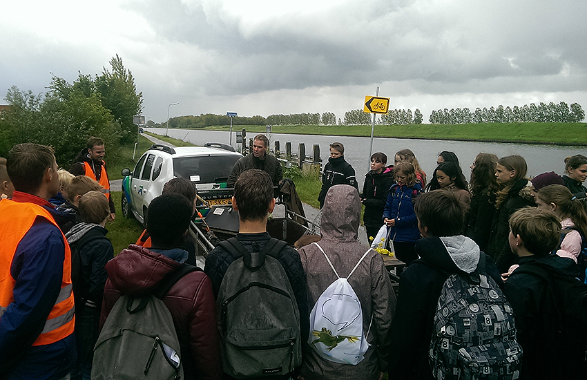 Leerlingen luisteren naar een waterschapper tijdens de Geoweek in waterschap Noorderzijlvest