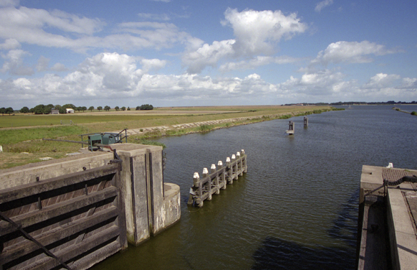 Zicht op water en weilanden vanaf een sluis.