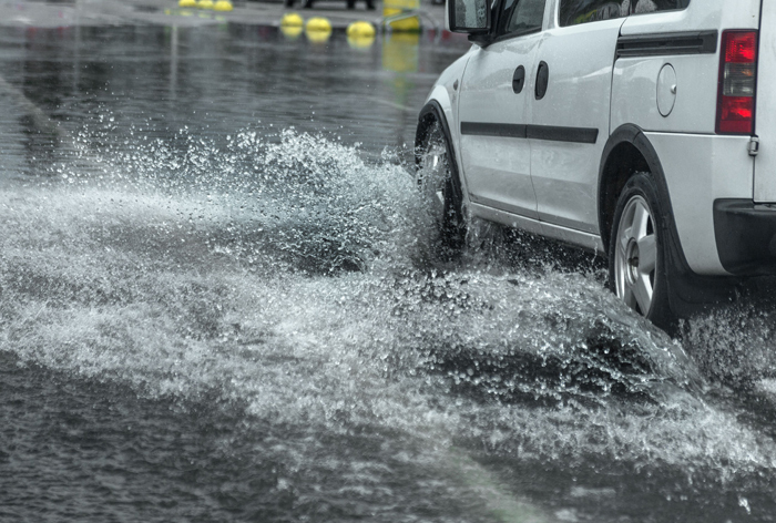 Auto rijdt door enorme regenplas